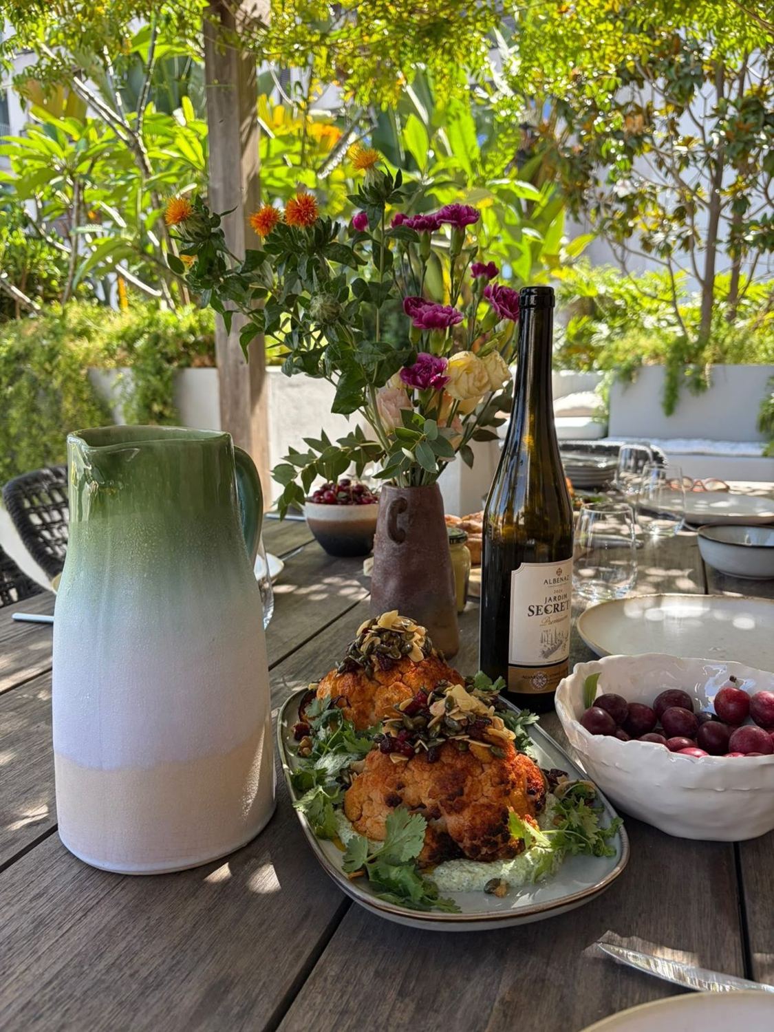 A private table with harissa cauliflower, flowers and wine
